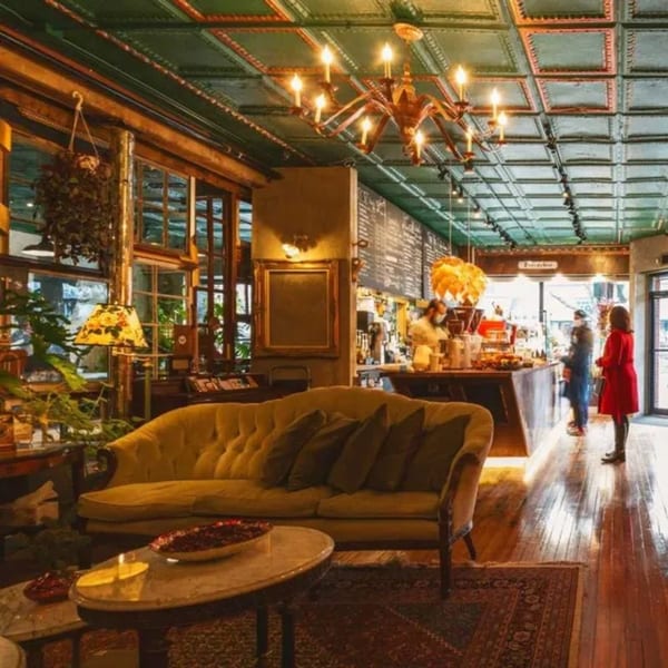 Cozy Pistachio Cafe interior with a yellow sofa, coffee bar, and customers at the counter.